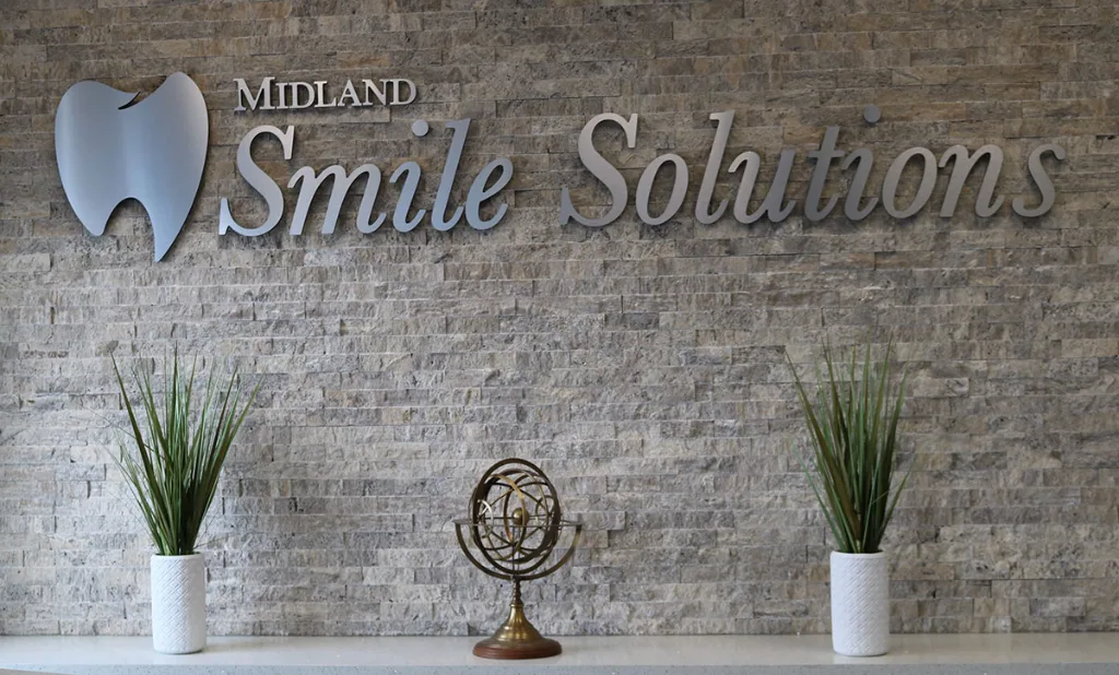 Smile Solutions sign on a stone wall in the clinic